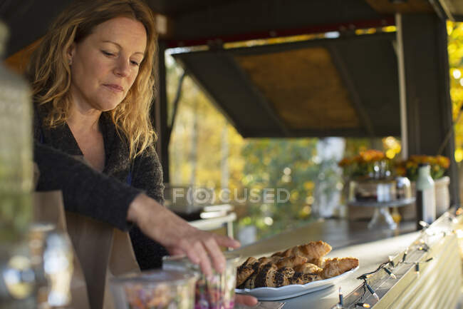 Propietaria de carrito de comida femenina arreglando pasteles - foto de stock