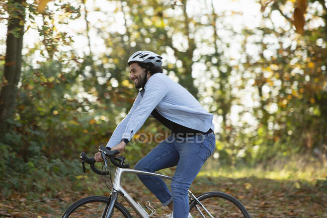 Happy young man riding bicycle in autumn park — Stock Photo