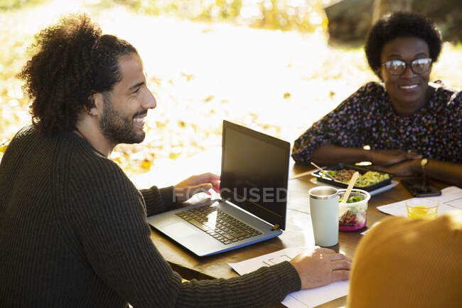 Щасливий бізнесмен з ноутбуком зустріч з колегами в парку — стокове фото