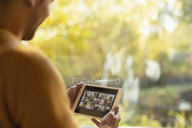Mann chattet mit Freunden auf digitalem Tablet-Bildschirm am Fenster — Stockfoto