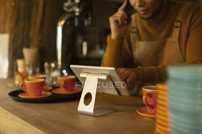Чоловіча бариста використовує цифровий планшет у кав'ярні — стокове фото
