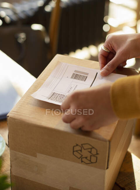 Close up business owner placing shipping label on box — Stock Photo