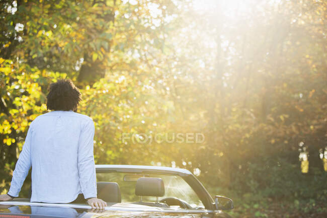 Unbekümmerter junger Mann im Cabrio im sonnigen, idyllischen Herbstpark — Stockfoto
