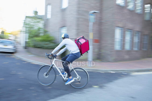 Male bike messenger delivering food on urban street — Stock Photo