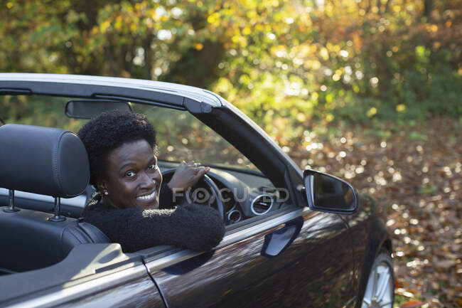Ritratto donna felice guida decappottabile nel parco autunnale — Foto stock