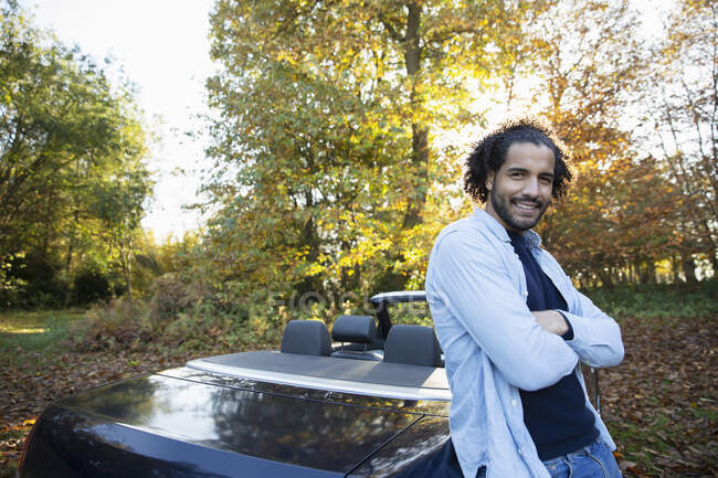 Portrait happy man at convertible in autumn park — Stock Photo