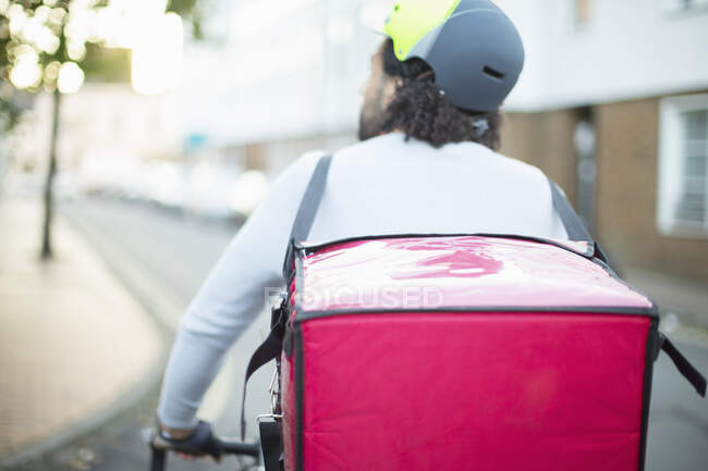 Mensageiro de bicicleta masculino no capacete entregando comida na rua urbana — Fotografia de Stock