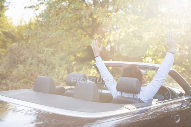 Carefree young man in convertible in sunny autumn park — Stock Photo