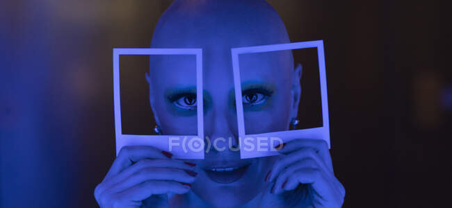 Bizarre portrait woman with shaved head holding polaroid cut outs — Stock Photo