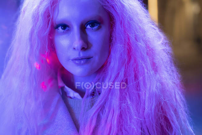 Primer plano retrato hermosa mujer con pelo rosa en luz de neón - foto de stock