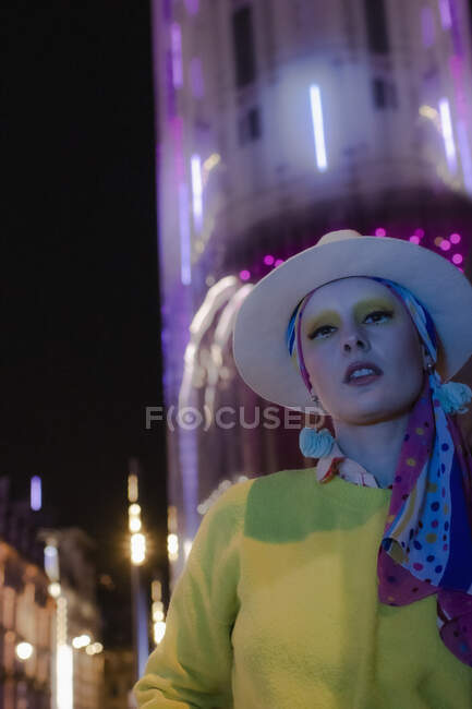 Portrait cool fashionable woman in fedora below city building at night — Stock Photo
