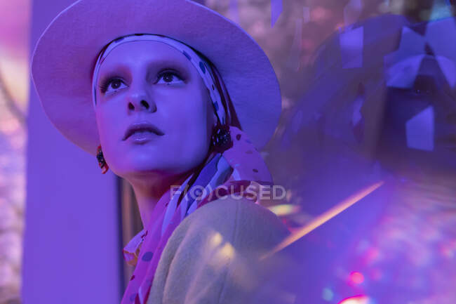 Portrait beautiful fashionable woman in fedora under neon lighting — Stock Photo