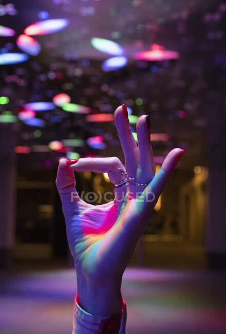 Chiudi donna gesticolando bene con la mano sotto le luci al neon — Foto stock