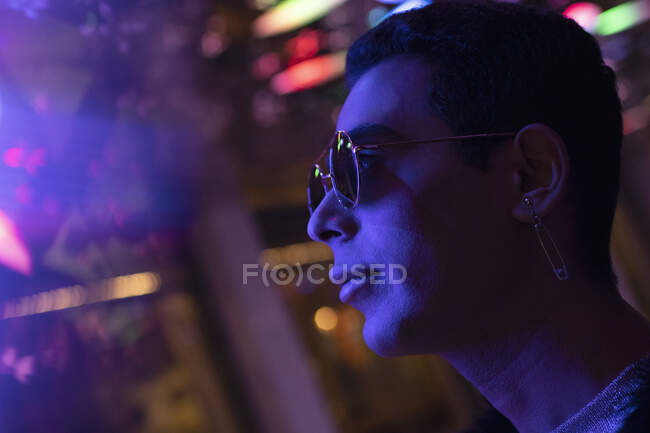 Close up elegante jovem em óculos de sol sob luz de néon — Fotografia de Stock