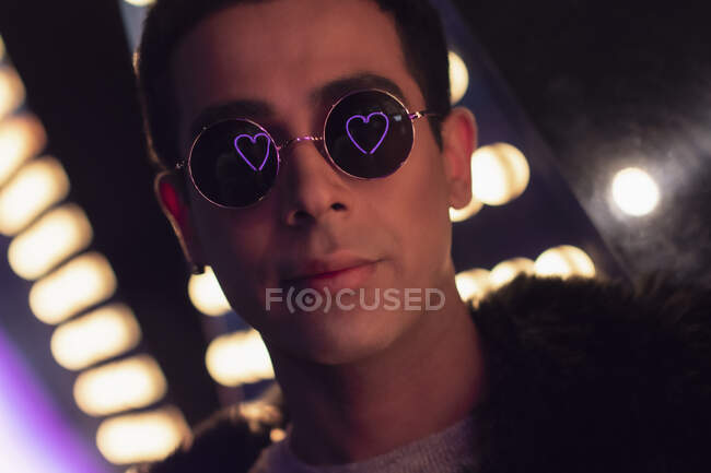 Portrait cool young man with neon heart reflection in sunglasses — Stock Photo