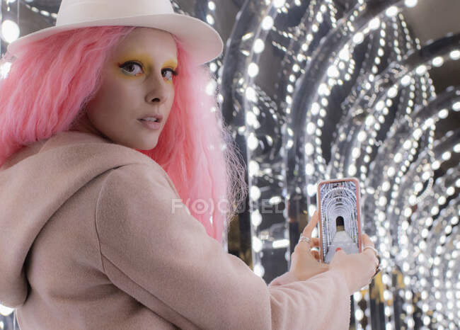 Retrato mujer con el pelo rosa y teléfono inteligente foto de las luces del arco - foto de stock