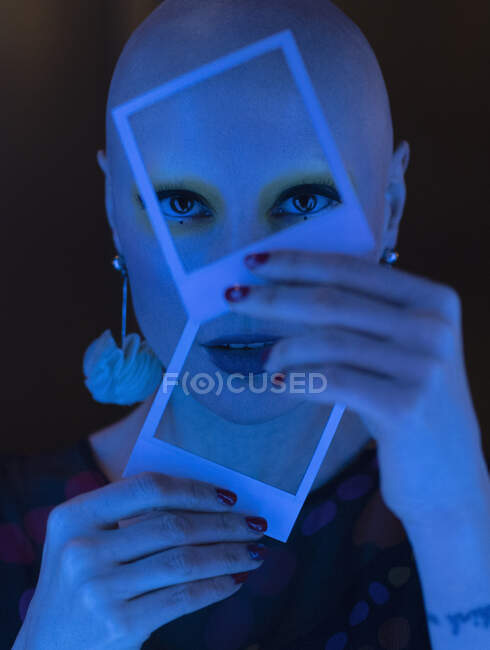 Close up portrait stylish woman with shaved head holding polaroids — Stock Photo