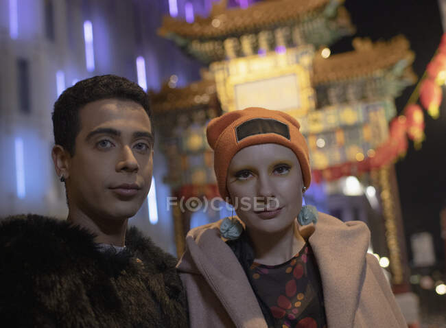 Portrait cool young couple at Chinatown gate at night, London, UK — Stock Photo