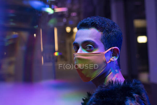 Ritratto elegante giovane uomo con orecchini spillo di sicurezza indossando maschera — Foto stock