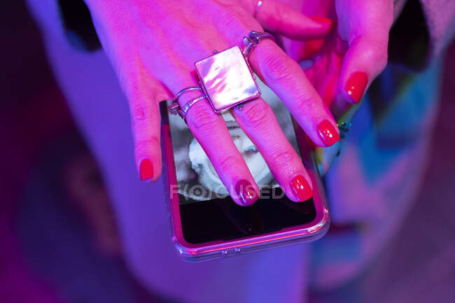 Cerca de la mano de la mujer con manicura roja que cubre el teléfono inteligente - foto de stock