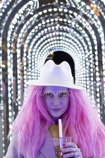 Ritratto donna alla moda con capelli rosa in fedora sotto luci ad arco — Foto stock