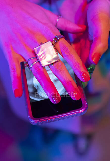Close up woman with manicure and rings covering smart phone screen — Stock Photo