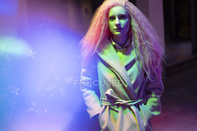 Ritratto donna elegante con capelli rosa in cappotto di lana in luce al neon — Foto stock