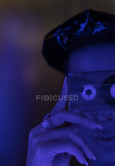 Primer plano elegante joven sosteniendo cinta de cassette sobre la cara - foto de stock