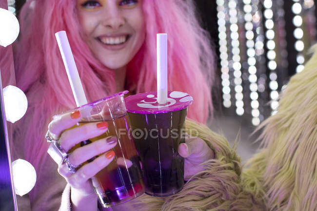 Mujer elegante feliz con el pelo rosa celebración de cócteles en taza desechable - foto de stock