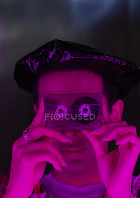 Retrato elegante jovem segurando fita cassete sobre o rosto — Fotografia de Stock