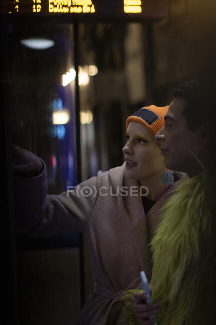 Elegante jovem casal esperando na parada de ônibus à noite — Fotografia de Stock