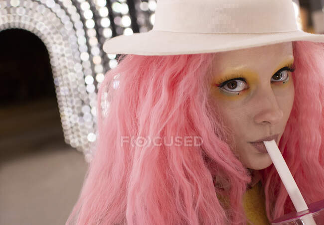 De cerca retrato mujer con estilo con el pelo rosa beber de paja - foto de stock