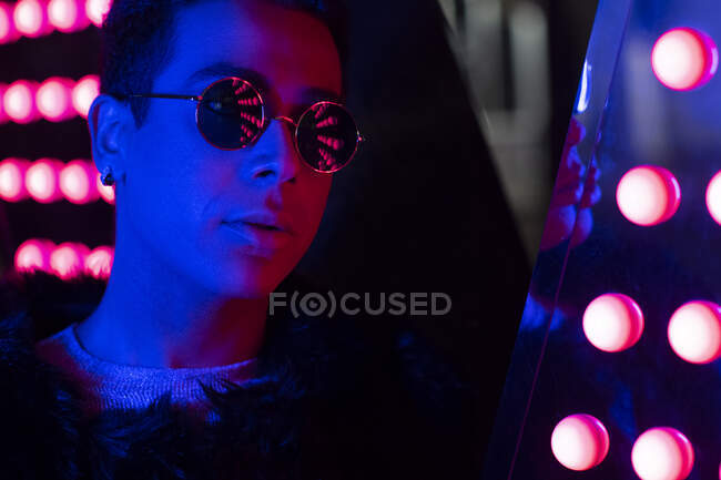 Close up portrait cool young man in sunglasses in neon lighting — Stock Photo