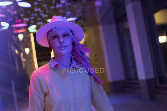 Portrait fashionable woman in fedora under neon lights — Stock Photo