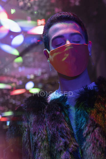 Stylish serene young man in fur coat and face mask — Stock Photo