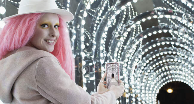Retrato mujer con estilo con el pelo rosa fotografiando las luces del arco - foto de stock
