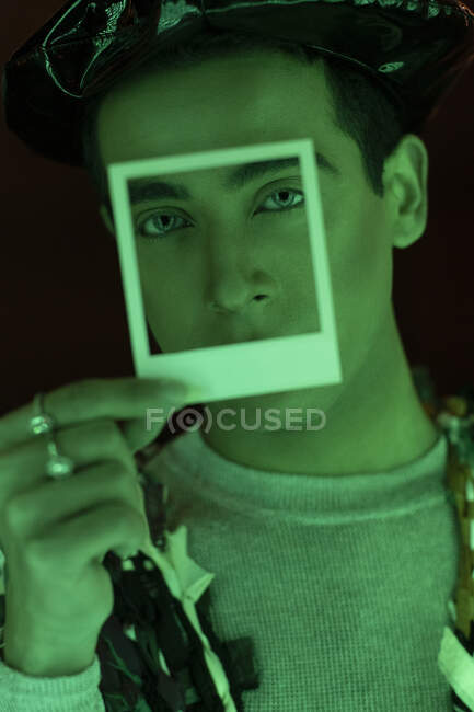 Retrato elegante bonito homem segurando polaroid sobre o rosto — Fotografia de Stock