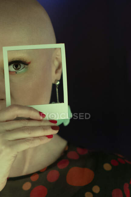 Retrato mulher elegante com a cabeça raspada segurando polaroid sobre o olho — Fotografia de Stock