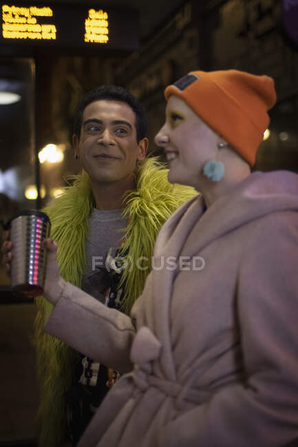 Casal feliz com café esperando na parada de ônibus à noite — Fotografia de Stock