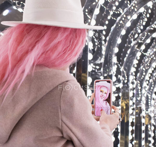 Schöne stilvolle Frau mit rosa Haaren macht Selfie unter Lichtern — Stockfoto