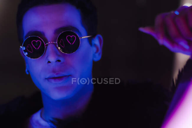 Porträt cooler junger Mann mit Sonnenbrille und Herz-Reflexion im Dunkeln — Stockfoto