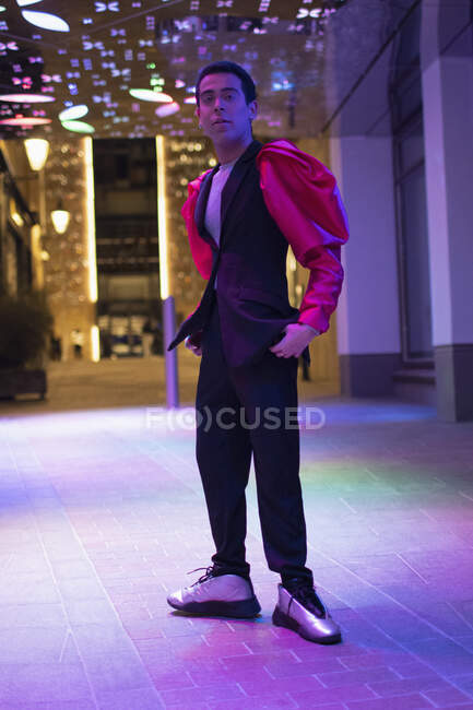 Portrait eccentric stylish young man under neon light in city at night — Stock Photo