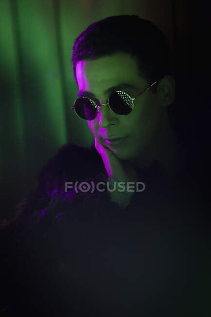 Stilvoller junger Mann mit Sonnenbrille in Dunkelheit — Stockfoto