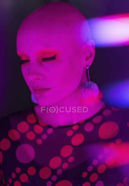 Stylish serene woman with shaved head in red light — Stock Photo