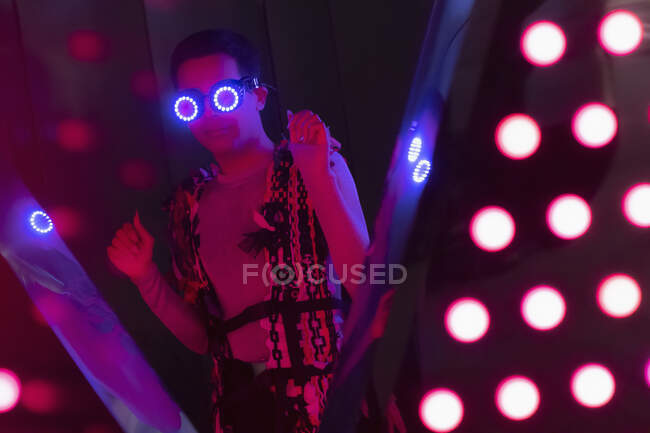 Portrait fashionable young man in futuristic neon glasses at nightclub — Stock Photo