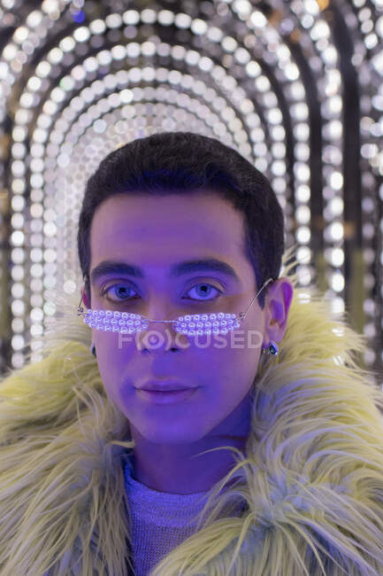 Portrait stylish young man in pear glasses under arch lights — Stock Photo