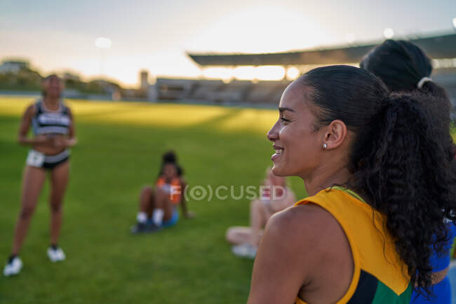 Sorrindo pista feminina e atleta de campo na grama do estádio — Fotografia de Stock