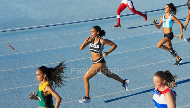 Female track and field athletes running in competition on blue track — Stock Photo
