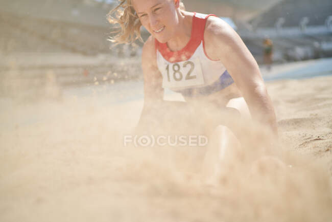 Female track and field athlete landing in long jump sand — Stock Photo