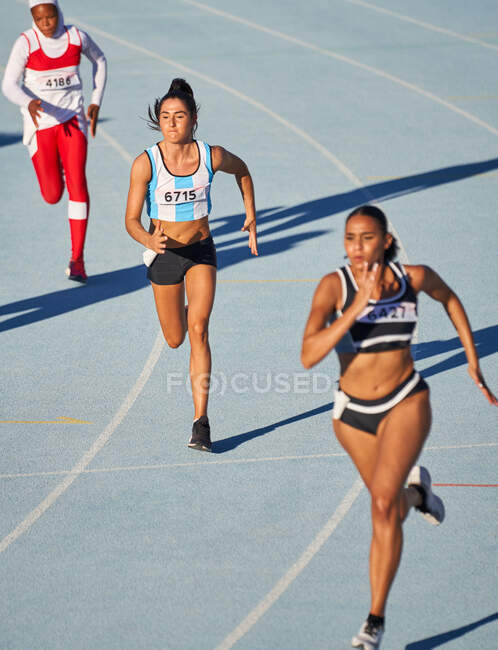 Female track and field athletes running on track in competition — Stock Photo